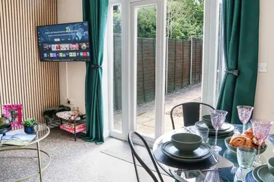 a dining room with green curtains and a table with a television at Stylish 2 Bedroom Property in Bury Saint Edmunds