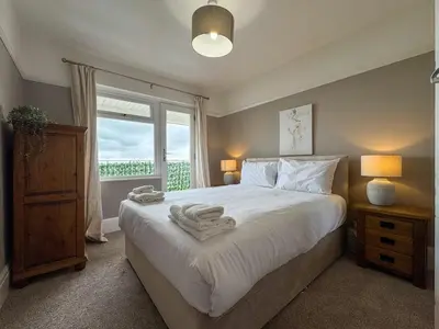 a bedroom with a large white bed with a window at Seafront Beach House in Southend-on-Sea