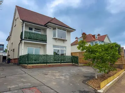 a house with a green fence in front of it at Seafront Beach House in Southend-on-Sea