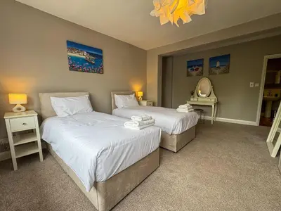 a bedroom with two beds and a mirror and a chandelier at Seafront Beach House in Southend-on-Sea