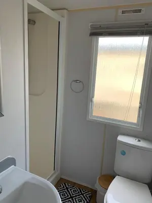 a bathroom with a white toilet and a window at Seawick holiday park caravan in Saint Osyth