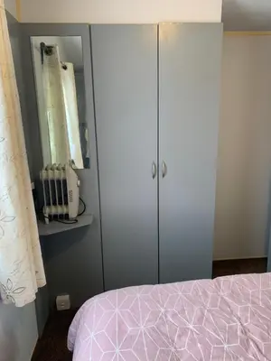 a bedroom with a bed and a cabinet at Seawick holiday park caravan in Saint Osyth