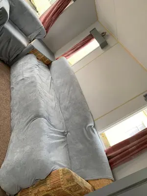 a couch in a room with a window at Seawick holiday park caravan in Saint Osyth