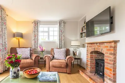 a living room with two chairs and a fireplace at Stunning estuary views - Riverside Cottage in Snape