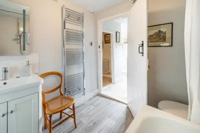 a bathroom with a sink and a chair next to a mirror at Stunning estuary views - Riverside Cottage in Snape
