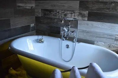 a bath tub with a shower in a bathroom at Long Melford Swan in Long Melford