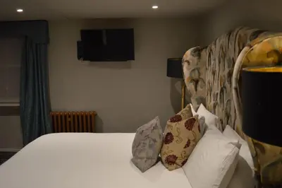 a bedroom with a bed and a tv on the wall at Long Melford Swan in Long Melford