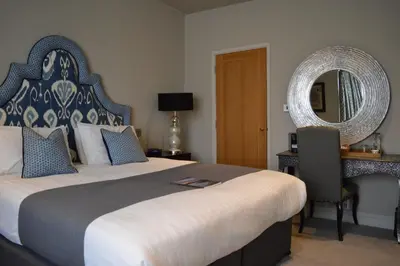 a hotel room with a large bed and a mirror at Long Melford Swan in Long Melford