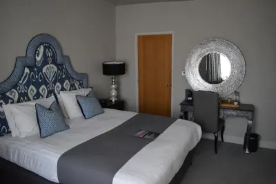 a bedroom with a large bed and a mirror at Long Melford Swan in Long Melford