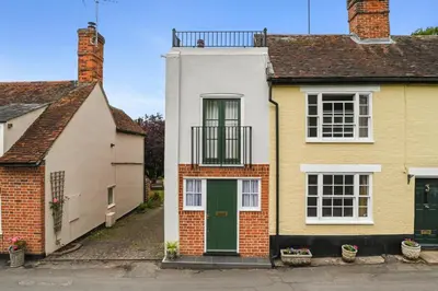 a white and yellow house with a green door at 28 Church Ponds, Castle Hedingham in Castle Hedingham
