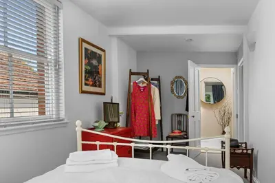 a bedroom with a bed and a red dress on a rack at 28 Church Ponds, Castle Hedingham in Castle Hedingham