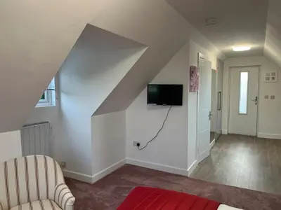 a living room with a staircase with a tv on the wall at Rubys cartlodge in Stambourne
