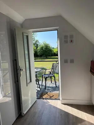 a door leading to a patio with a chair outside at Rubys cartlodge in Stambourne