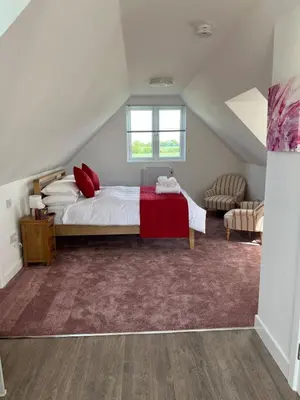a bedroom with a large bed with red pillows at Rubys cartlodge in Stambourne