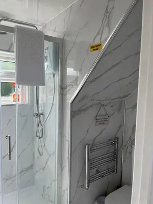 a bathroom with a shower with a marble wall at Rubys cartlodge in Stambourne