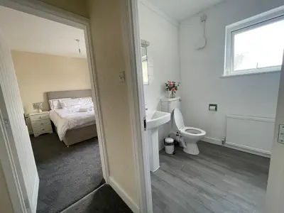 a bathroom with a sink and a toilet and a bed at Ouse River Quay Hill Lodge in Littleport
