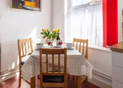 a dining room table with a vase of flowers on it at Pebbles, King St - Aldeburgh Coastal Cottages in Aldeburgh