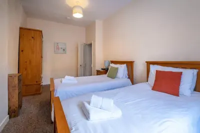 a bedroom with two beds with white sheets and red pillows at Pebbles, King St - Aldeburgh Coastal Cottages in Aldeburgh