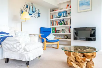 a living room with a glass table and a blue chair at Samphire in Aldeburgh