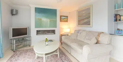a living room with a couch and a table and a tv at 5 The Sanctuary, Thorpeness - Aldeburgh Coastal Cottages in Thorpeness