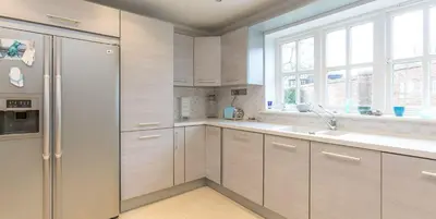 a kitchen with white cabinets and a refrigerator at 5 The Sanctuary, Thorpeness - Aldeburgh Coastal Cottages in Thorpeness