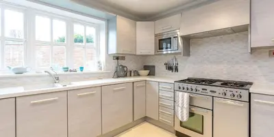 a kitchen with white cabinets and a stove top oven at 5 The Sanctuary, Thorpeness - Aldeburgh Coastal Cottages in Thorpeness