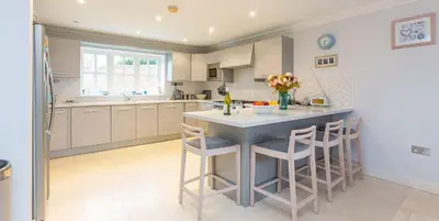 a kitchen with a large island with bar stools at 5 The Sanctuary, Thorpeness - Aldeburgh Coastal Cottages in Thorpeness