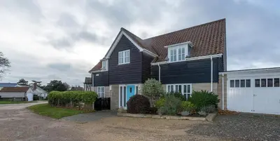 a black and white house with a white garage at 5 The Sanctuary, Thorpeness - Aldeburgh Coastal Cottages in Thorpeness