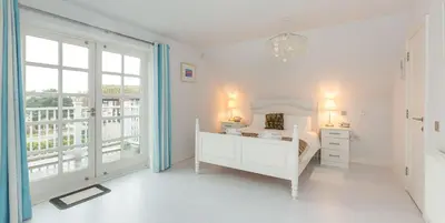 a white bedroom with a bed and a window at 5 The Sanctuary, Thorpeness - Aldeburgh Coastal Cottages in Thorpeness