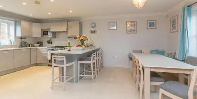 a kitchen with a table and some chairs in it at 5 The Sanctuary, Thorpeness - Aldeburgh Coastal Cottages in Thorpeness