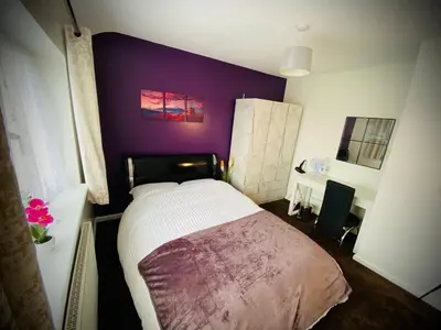 a bedroom with a bed and a purple wall at Modern-PetFriendly-privateGarden-Family-20MinToLDN in Stevenage