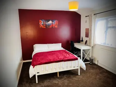 a bedroom with a bed with a red wall at Modern-PetFriendly-privateGarden-Family-20MinToLDN in Stevenage