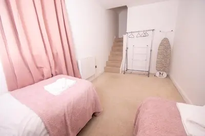 a bedroom with a pink bed and a staircase at Newly Renovated Sanctuary for 4 in Tacket Street, Ipswich in Ipswich