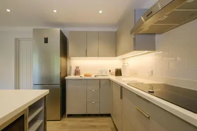 a kitchen with white cabinets and a stainless steel refrigerator at 8 Sanctuary, Very close to Thorpeness Meare and the beach - Aldeburgh Coastal Cottages in Thorpeness