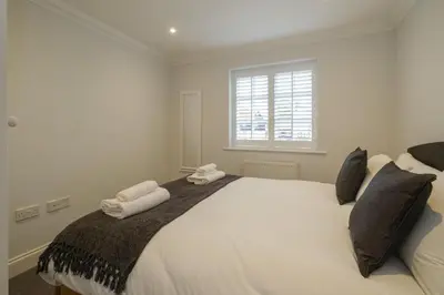 a bedroom with a large white bed with two towels at 8 Sanctuary, Very close to Thorpeness Meare and the beach - Aldeburgh Coastal Cottages in Thorpeness