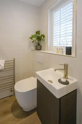 a white bathroom with a toilet and a sink at 8 Sanctuary, Very close to Thorpeness Meare and the beach - Aldeburgh Coastal Cottages in Thorpeness