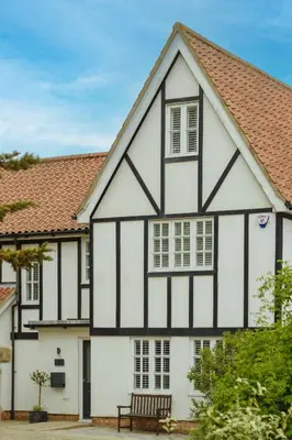 an old black and white house with a bench at 8 Sanctuary, Very close to Thorpeness Meare and the beach - Aldeburgh Coastal Cottages in Thorpeness