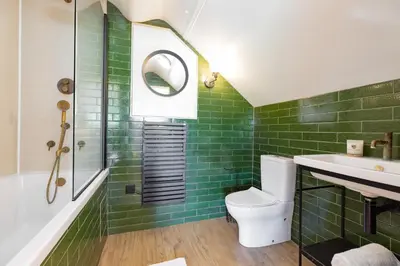 a bathroom with green tiles and a sink and a toilet at Fairytale Staycation - Near London by Damask Homes in Stapleford Tawney