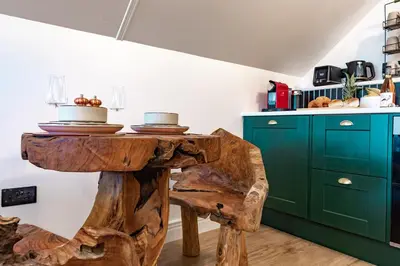 a kitchen with a wooden table and green cabinets at Fairytale Staycation - Near London by Damask Homes in Stapleford Tawney