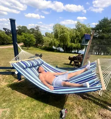 a man laying in a hammock in a park at Lakeview Petting Pod in Chelmsford