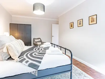 a white bedroom with a bed and a chair at Stylish 2-Bedroom Flat in Great Warley – Sleeps 6 Pass the Keys in Great Warley Street