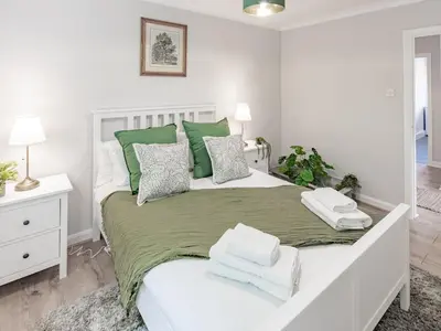 a white bedroom with a large bed with green and white pillows at Stylish 2-Bedroom Flat in Great Warley – Sleeps 6 Pass the Keys in Great Warley Street