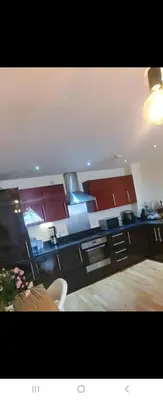 a kitchen with red cabinets and a wooden table at 1 bed luxurious flat in Basildon