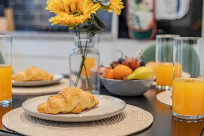 a table with plates of food and glasses of orange juice at Stylish Southend Stay in Southend-on-Sea
