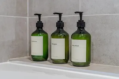 three bottles of green liquid sitting on a shelf in a bathroom at Stylish Southend Stay in Southend-on-Sea