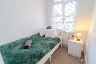a bedroom with a bed with a green blanket and a window at Stylish Southend Stay in Southend-on-Sea