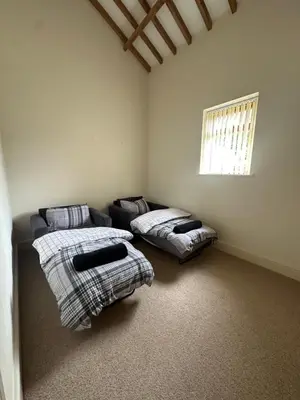 a living room with two beds and a window at The Old stables Barn in Old Hurst