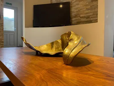 a gold shoe sculpture sitting on a wooden table at 4-Bed Barnwell Retreat- Sleeps10 Garden & Parking in Stevenage