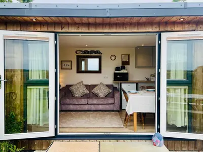 a living room with sliding glass doors and a couch at Romantic Cabin Retreat on 50-Acre Suffolk Farm in Burgh