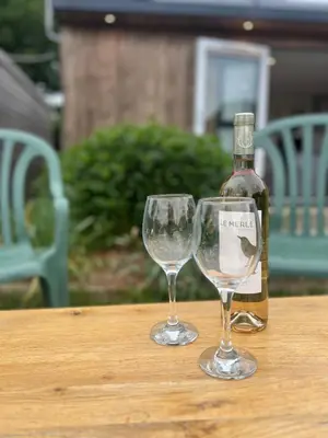 two wine glasses sitting on a table with a bottle at Romantic Cabin Retreat on 50-Acre Suffolk Farm in Burgh